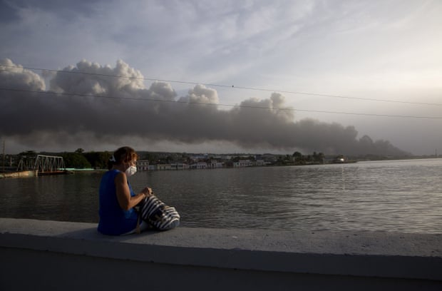 Un residente se sienta en el dique del Malecón mientras el humo se eleva en el fondo del fuego.