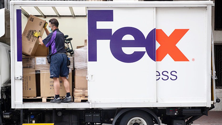 Un trabajador de FedEx recibe paquetes de un camión.