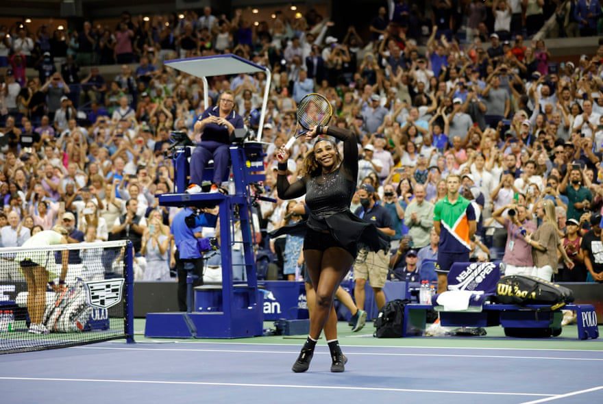 Serena Williams levanta su raqueta y su brazo hacia la multitud mientras se para en la cancha después de su victoria.