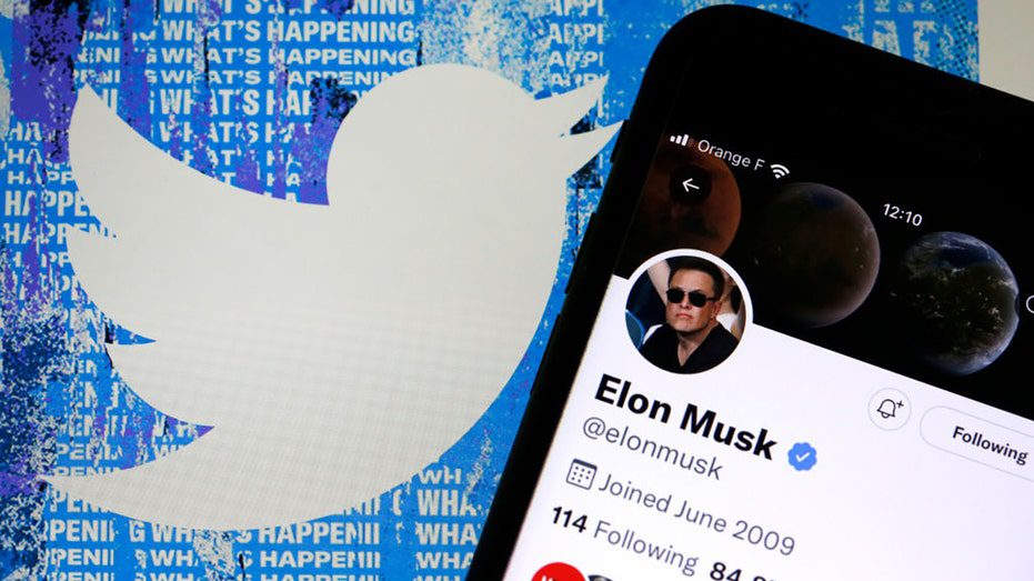 La cuenta de Twitter de Elon Musk se muestra en la pantalla del iPhone frente a la página de inicio del sitio web de Twitter.